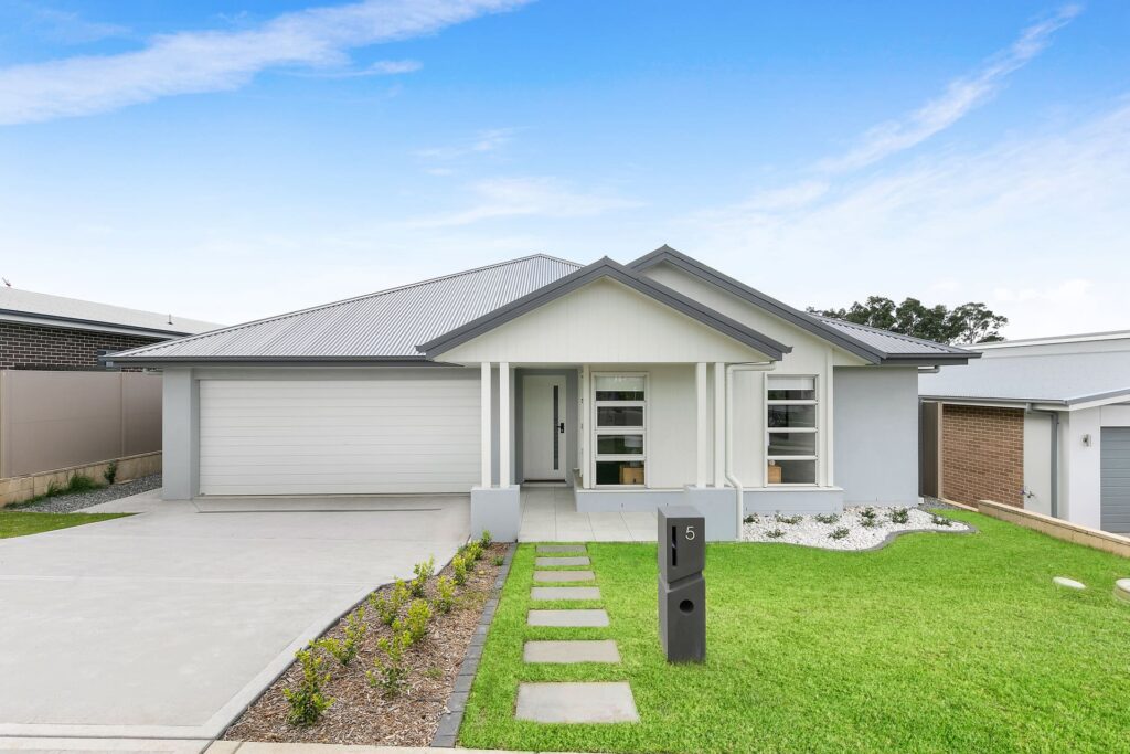 Modern single-story house with white exterior and manicured front lawn