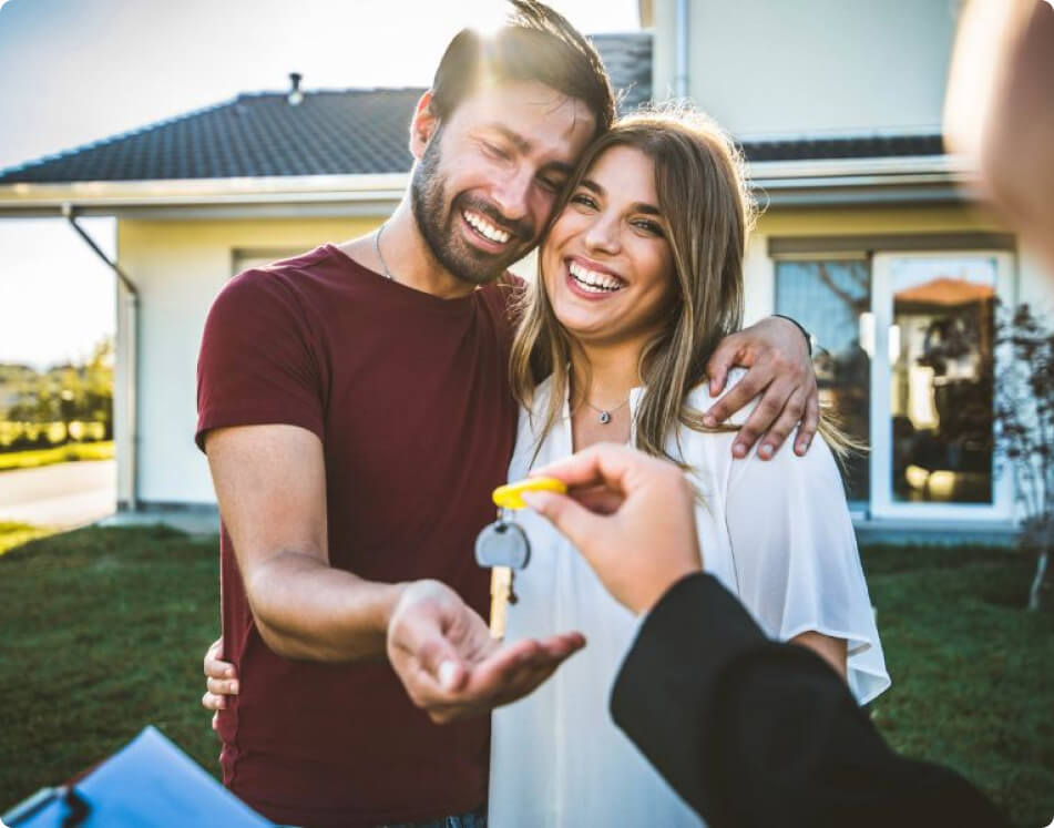 Happy couple receiving house keys in front of new home