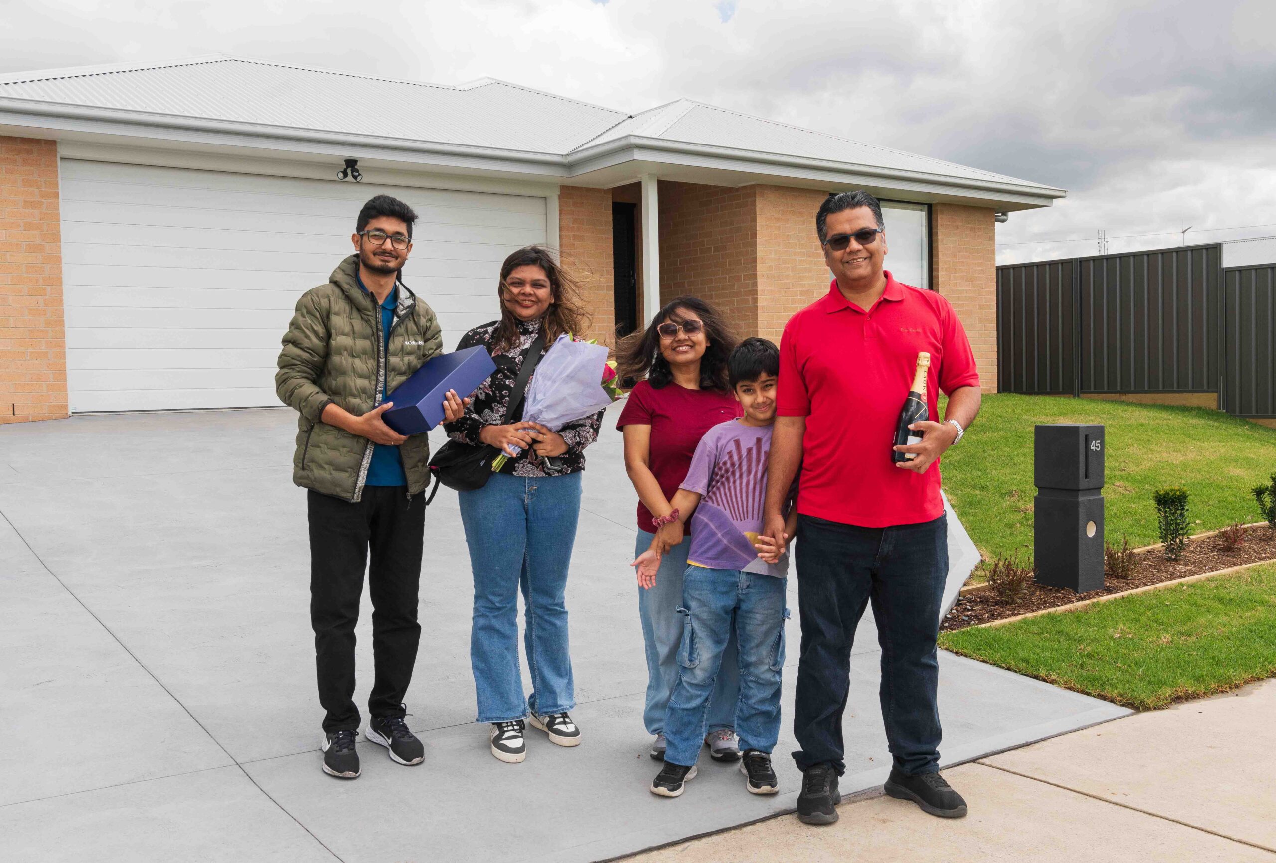 Happy family with gifts outside new home